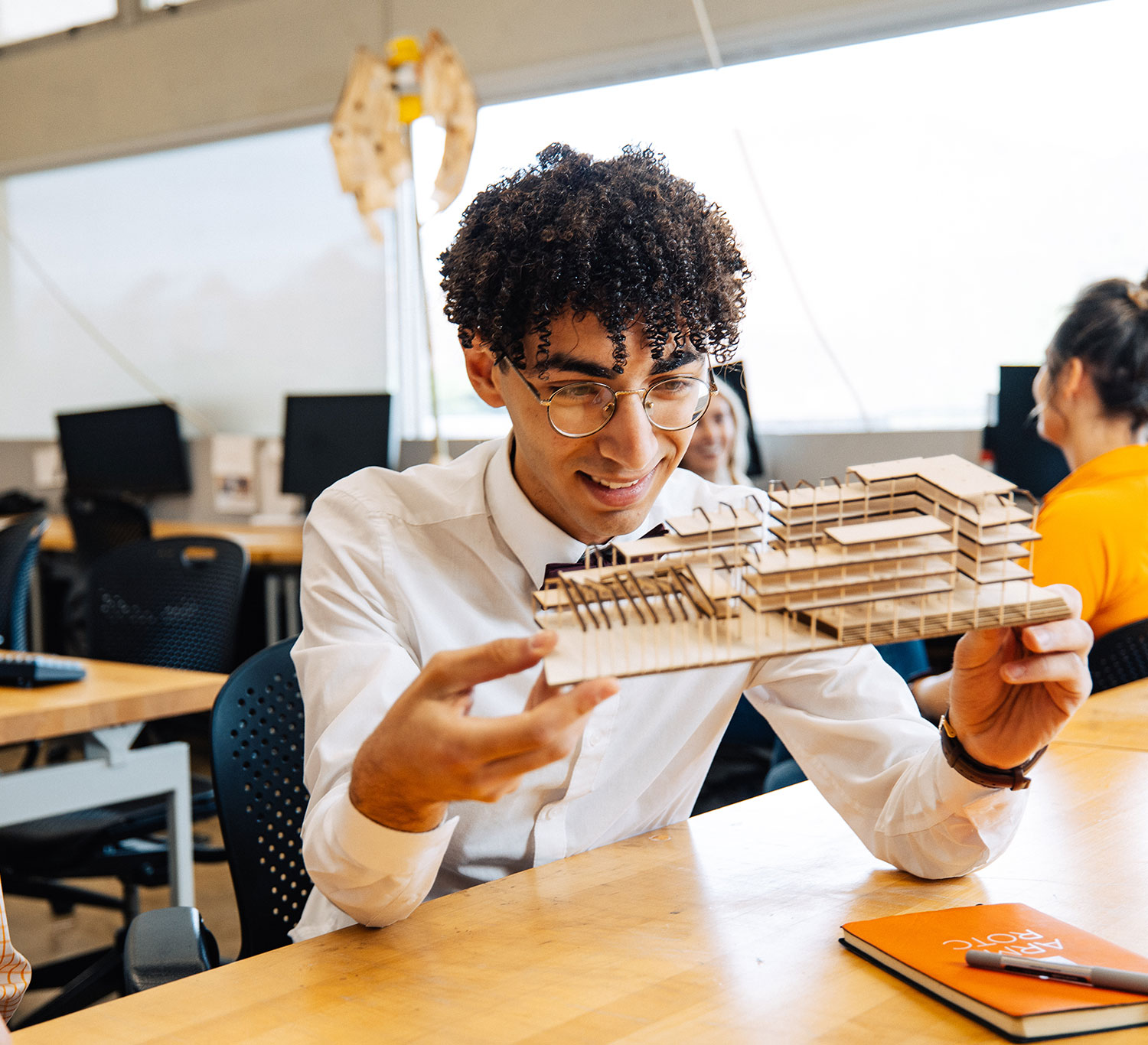 An architecture student inspects a recently created model of a multi-story building